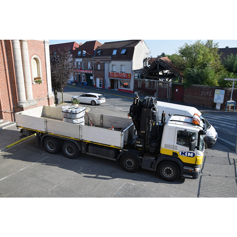 step 1 of the return of the font to Gondecourt St-Martin: the font padded in protective wrapping on the bed of a truck; the door on the left is in the west entranceway to the church