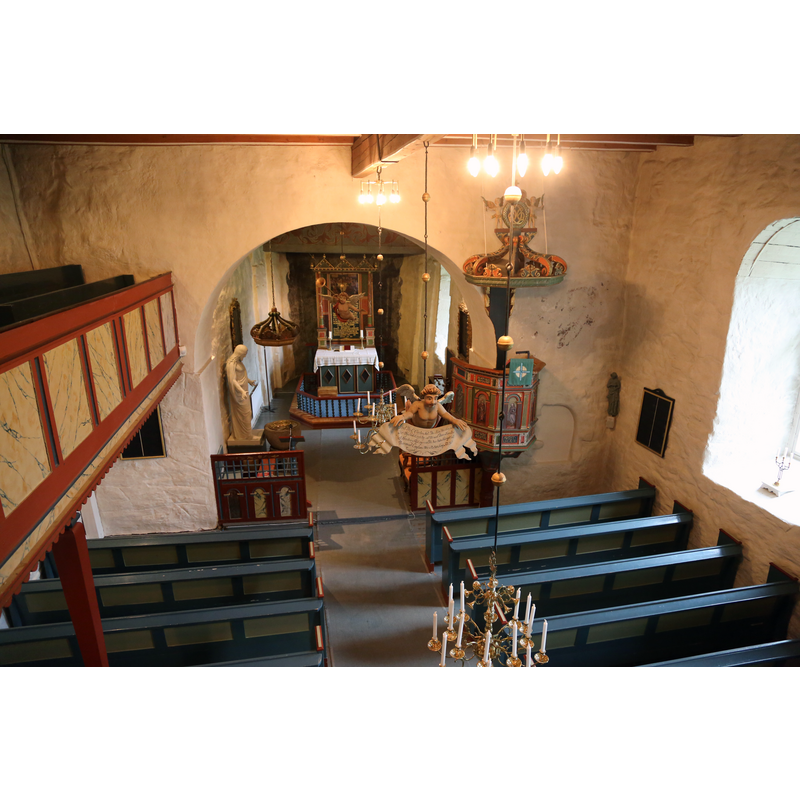 the photograph, taken from the upper gallery, shows the canopy, the statue and the font by the left [north] side of the chancel arch