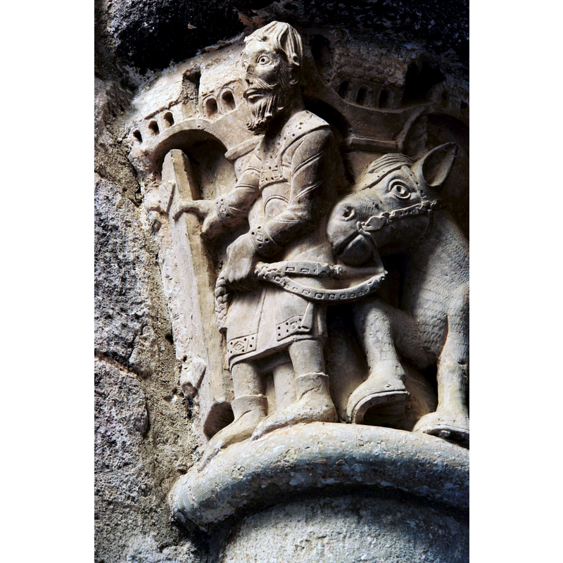 One of a series of capitals on the Childhood of Christ cycle in this church: the Flight to Egypt -- Joseph opens a door or gate as he leads Mary and the Child Christ on the horse; the building by his left shoulder is part of the background of the scene, showing a fortified town into which the Family are about to enter --notice the detailed work on the man's head, his garments, and the horse's bridle; both man and animal are shoed.