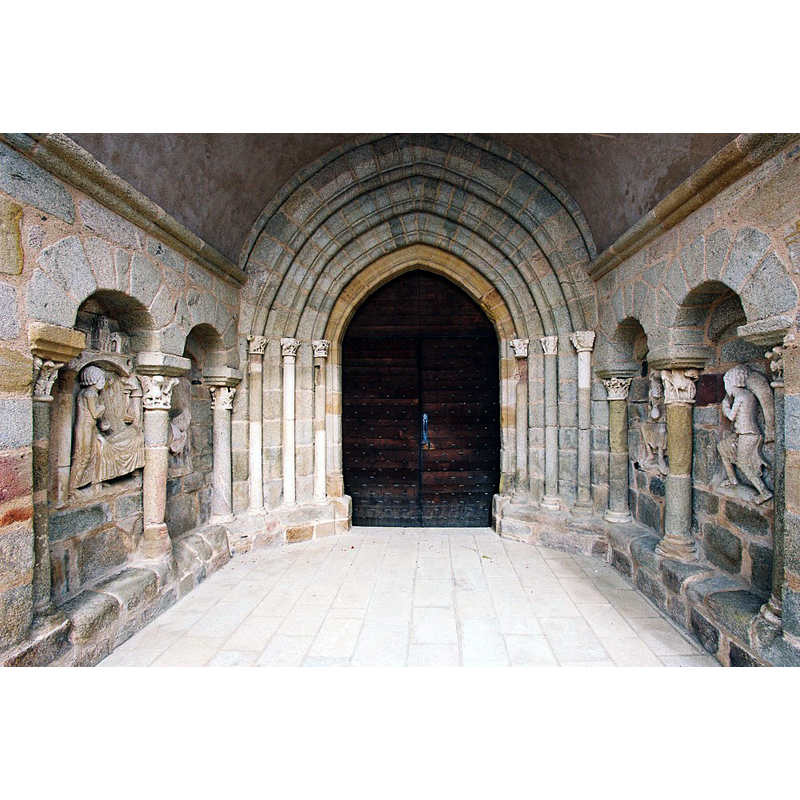 Source caption: "Au fond des arcades sont encastrées des plaques de calcaire, mais l’usure du temps a rendu celles du nord peu lisibles. On y voyait jadis la parabole de Lazare et du mauvais riche. Sur le mur sud se déroule, à gauche, le supplice de l’avare. Le relief voisin, le mieux conservé. montre un homme pieds nus, fléchissant sous le poids d’un énorme poisson. Il s’agirait d’illustrer le vice de la gourmandise, reproché comme l’avarice, au mauvais riche...Ce décor raffiné, datable du milieu du XIIe siècle, s’apparente au porche d’Ydes, dans le Cantal, et aux chapiteaux de l’abside de Sainte-Marie de Souillac."