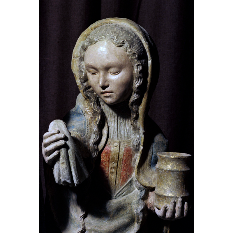 Source caption: "Bordant l’église, le cimetière possède une chapelle qui renferme une remarquable Mise au Tombeau groupant six personnages autour du Christ étendu sur le linceul dont Nicodème et Joseph d’Arimathie soulèvent les extrémités. Derrière le tombeau se tient la Vierge, douloureuse et recueillie, entourée de saint Jean l’Evangéliste et des « trois Marie », Cléophas, Salomé et Madeleine reconnaissable à son vase d’aromates."