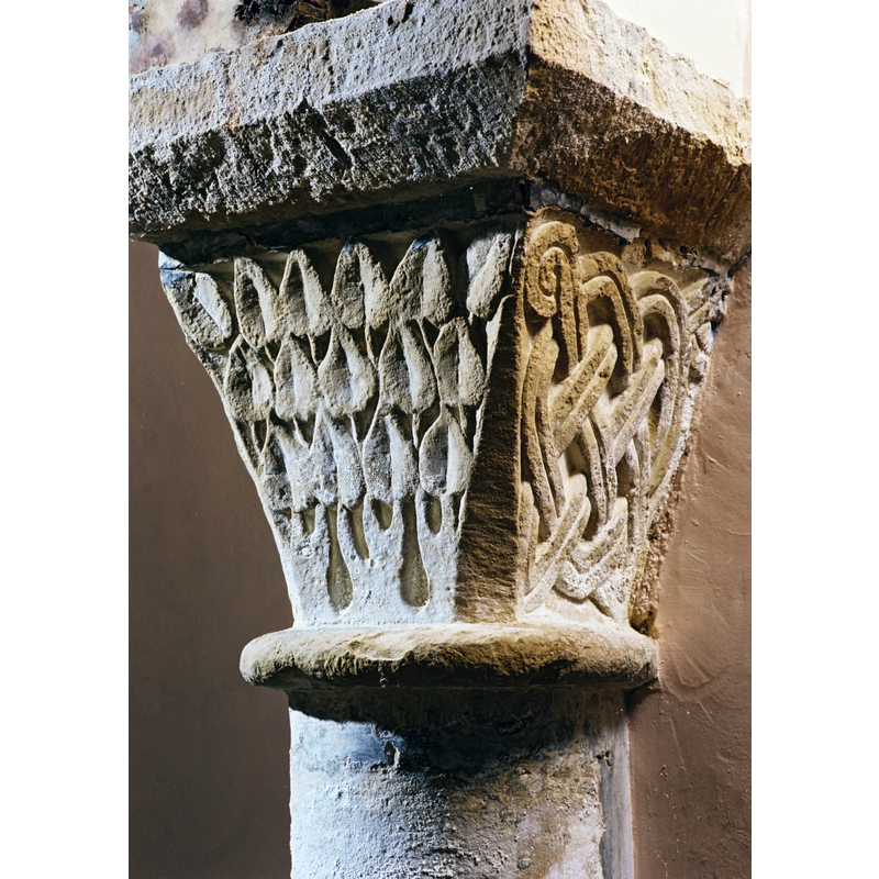 Source caption: "Du décor sculpté, également très restauré, subsistent quelques éléments originaux. dans la partie orientale de l’église. Les entrelacs géométriques et les motifs végétaux alternent sur les corbeilles des chapiteaux."