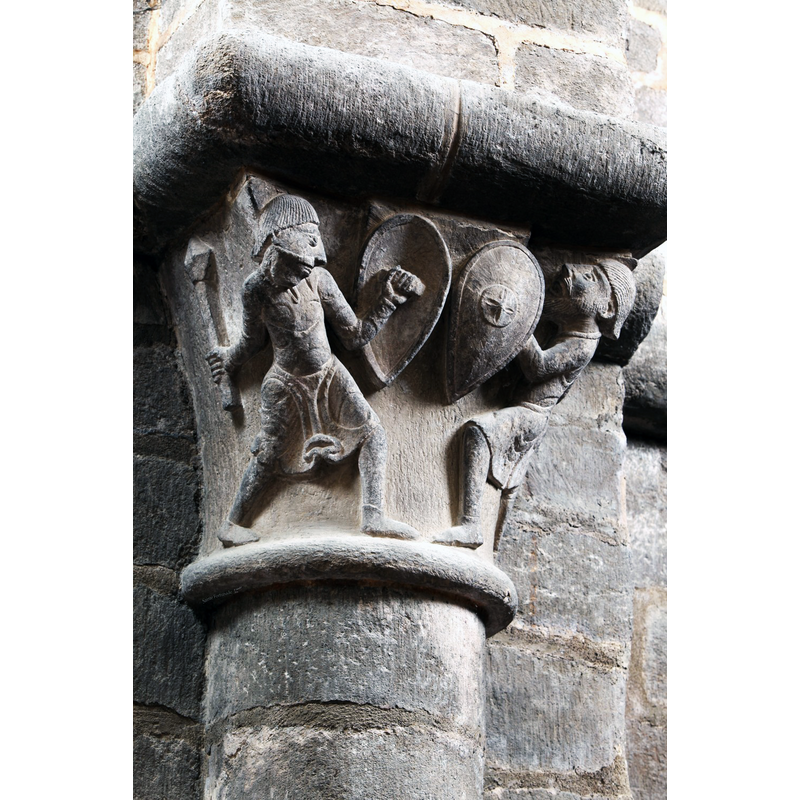 Source caption: "Un autre chapiteau montre, dans des attitudes d’une véracité remarquable, deux guerriers s’affrontant, protégés par leurs boucliers."