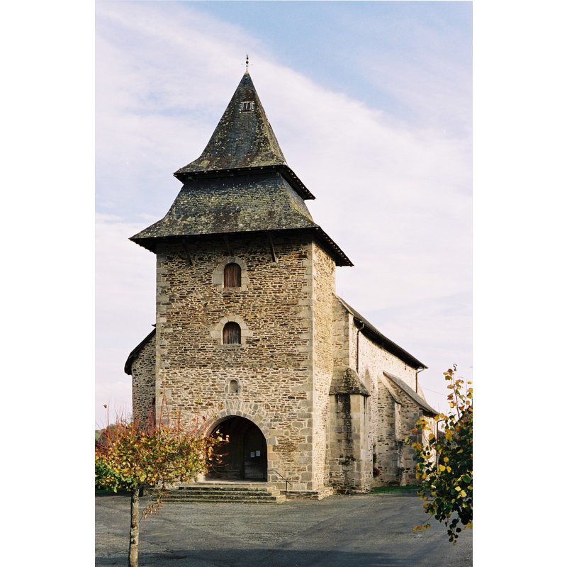 Source caption: "L’église présente une façade massive en forme de tour, surmontée d’un clocher en charpente coiffé de deux toitures superposées."