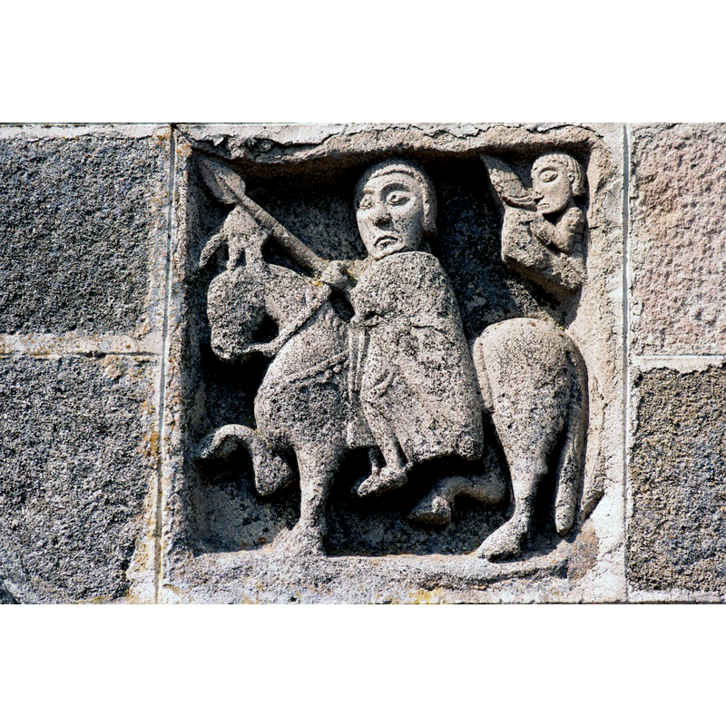 Source caption: "L’accès à l’église se fait, au nord, par un portail décoré de plusieurs archivoltes. De part et d’autre ont été encastrés deux bas-reliefs, accompagnés d’inscriptions, provenant de l’édifice primitif. Le premier représente saint Georges à cheval".