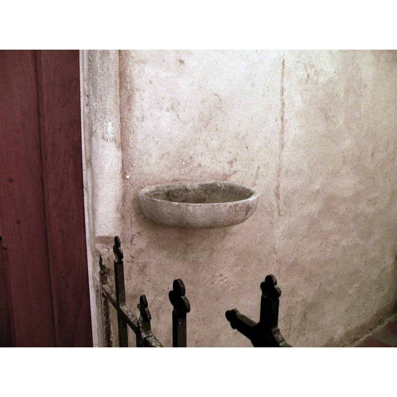 wall-mounted stoup located next to the doorway and near the font