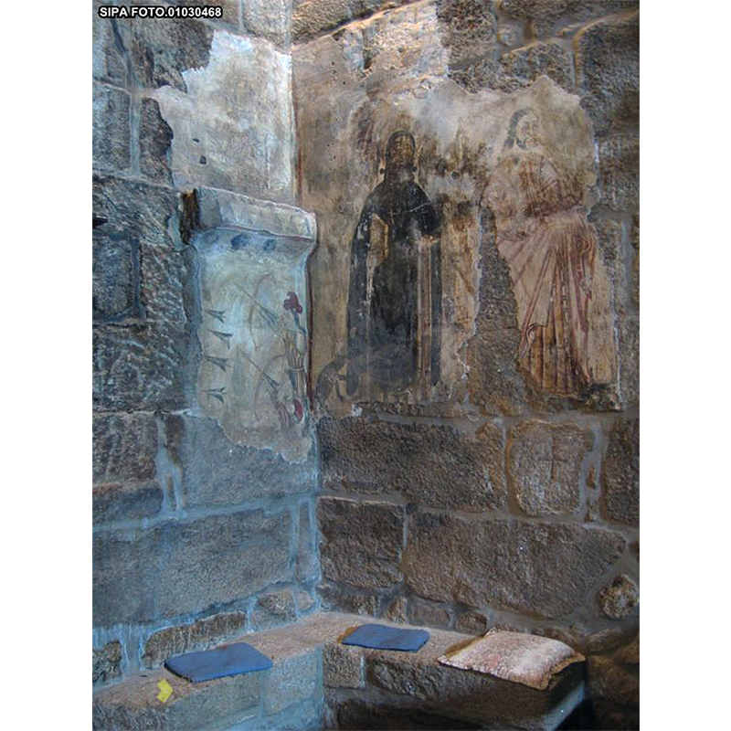 Source caption: "vestígios de pintura mural na parede do arco triunfal e parede da nave adjacente, a cerca de um metro do nível do pavimento actual, e na parede testeira da capela-mor, atrás do retábulo-mor apenas alguns padrões decorativos. Na parede da nave, do lado do Evangelho, e de O. para E., surge representado um santo franciscano, talvez Santo António, sobre peanha, descalço e com livro sobre o braço esquerdo dobrado e crucifixo (?) na mão direita; 2 registos acima figura uma cena da vida de São Roque (São Roque no bosque) e, em baixo, os reis magos Melchior e Gaspar representação que se prolonga pela parede do arco triunfal (registo baixo) onde surge o terceiro Mago, Baltasar, não tendo, no entanto, sobrevivido o resto da cena que incluiria Nossa Senhora com o Menino, embora subsista a parte lateral do trono da Virgem e fragmento do seu manto. Sobre Baltasar, no registo alto, subsiste a parte inferior da representação de um santo, de pés descalços. No arco triunfal, do lado da Epístola surge, no registo alto, o tema do "Homem Silvestre", sentado, e em baixo, um fragmento do Martírio de São Sebastião. Na parede da nave adjacente à do arco triunfal, do lado da Epístola, existe a representação de Santo Antão e de São Bartolomeu."
