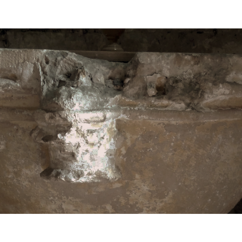 this one badly damaged, as its surrounding area; the damage was probably caused by the expansion of the metal anchorage for an old cover -- the colonnettes that matched the three capitals are missning, as is the original lower base