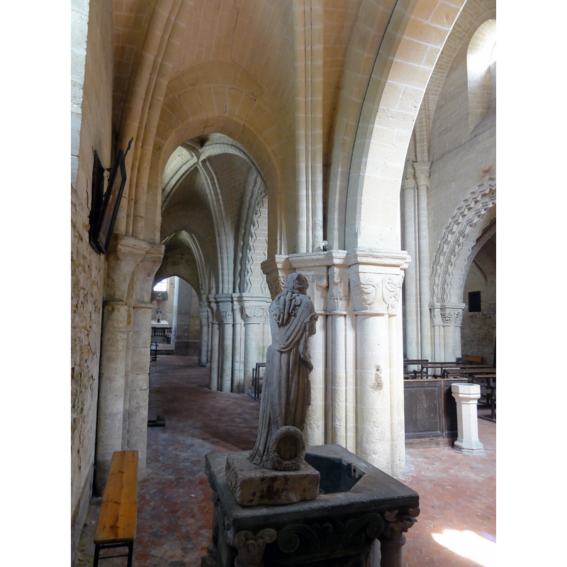 Source caption: "Bury (60), église Saint-Lucien, bas-côté nord, chapelle baptismale". -- the stone statue stands on the northwest side of the font, resting partly on the remains of the old cover, not visible in tnis image
