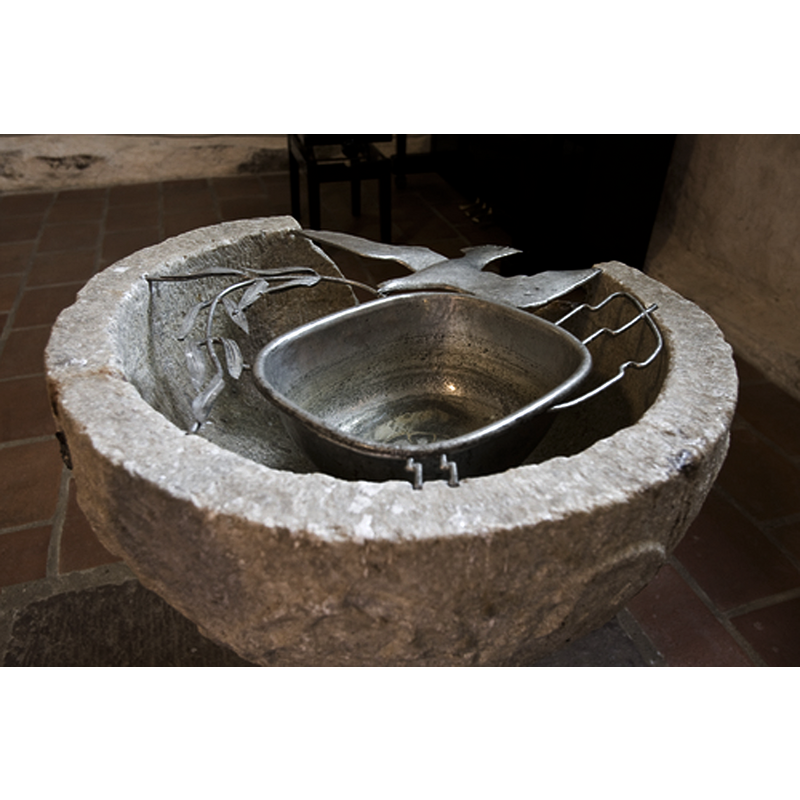 the fragment of a stome font is still used for baptisms with a metal baptismal dish resting on its upper rim