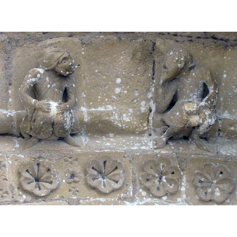 Source caption: "Ce couple figure la luxure. La femme relève sa robe pour montrer ses attributs féminins masqués pudiquement par du plâtre, l'homme tient sa verge mutilée. Bien qu'au moyen âge la pudeur telle que nous la concevons n'existe pas, ce genre de sculpture est très rare."