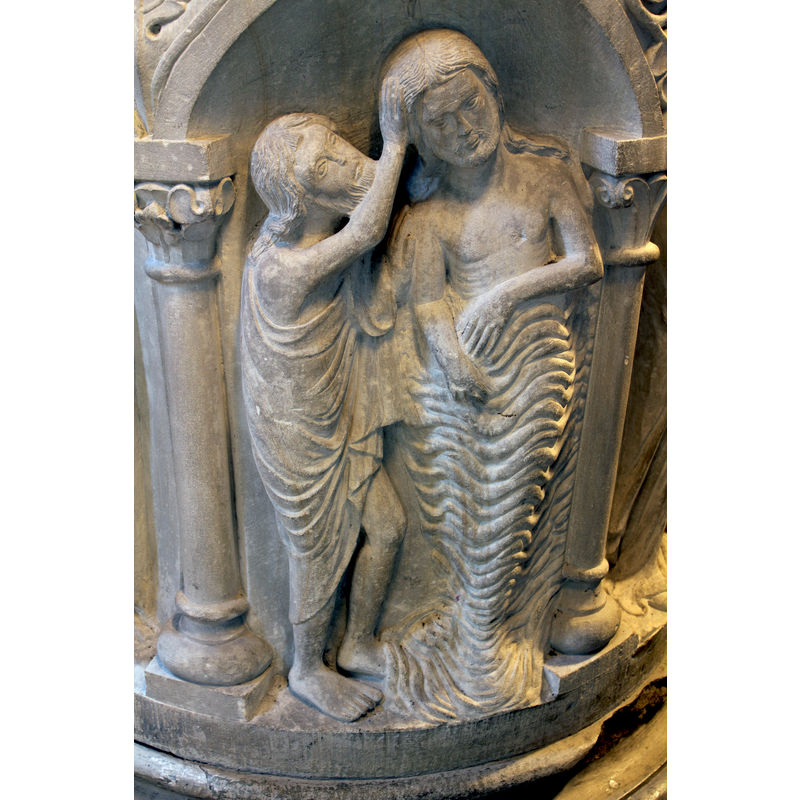 John the Baptist has his right ranhd on Christ's head, his left hand on Christ's shoulder; a tall Christ 'wears' the waters of the Jordan