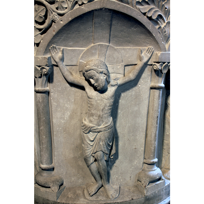 Christ wearing a cruciferous halo; wide cross; no wounds or nails visible; legs bent at the knees, feet resting on the ground