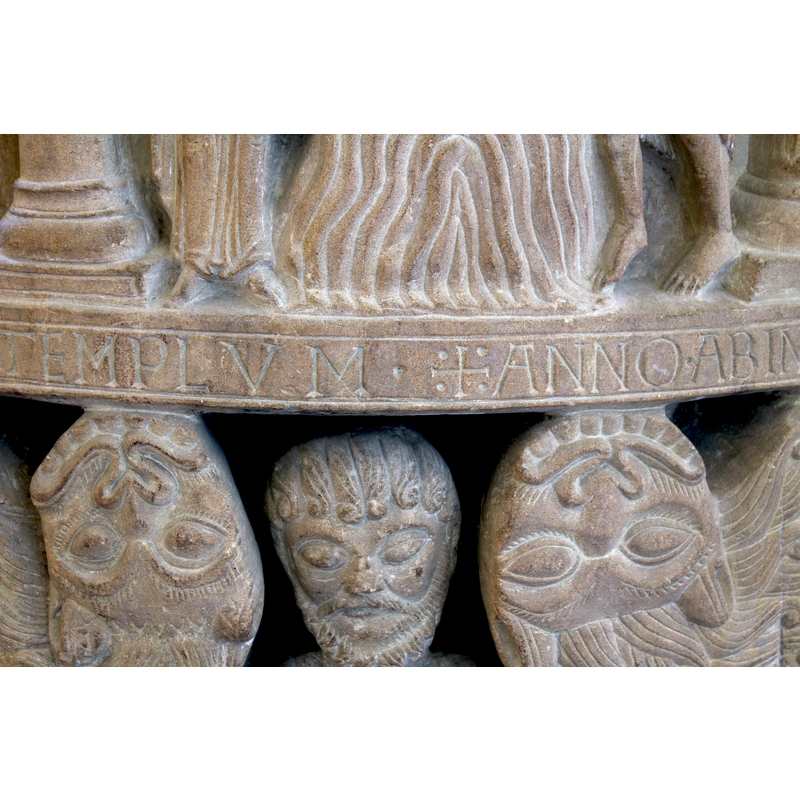 abve the head of Daniel and two smirking upside-down lions' heads