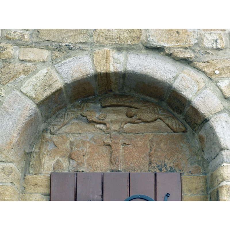 a damaged tympanum with a Crucifixion scene, a pair of angels above