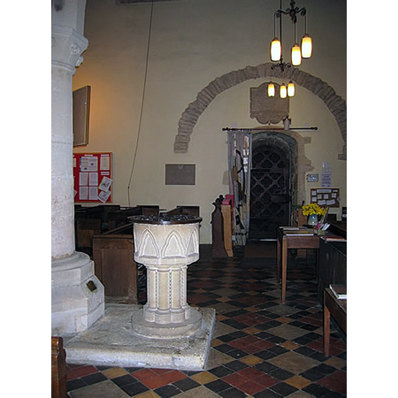 Source caption: "Font, 1921 copy of original Norman font, removed and lost during 18th century restoration work. Blocked Romanesque arch, may be Saxon, or placed in Saxon wall when Normans added aisles"