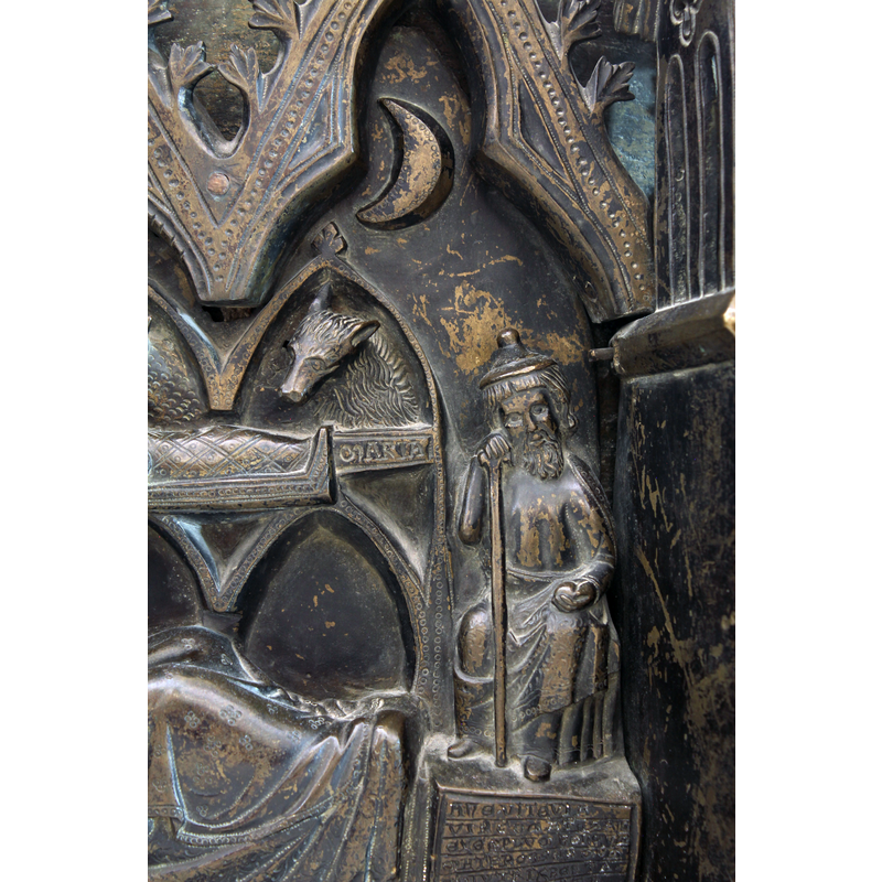 Joseph seated on the right, a staff in his right hand appears to support also his Jew-hatted head; a round object held in his left hand; the pedestal on which he is raised has an inscription; above his head, a Moon in a trefoiled arch-head