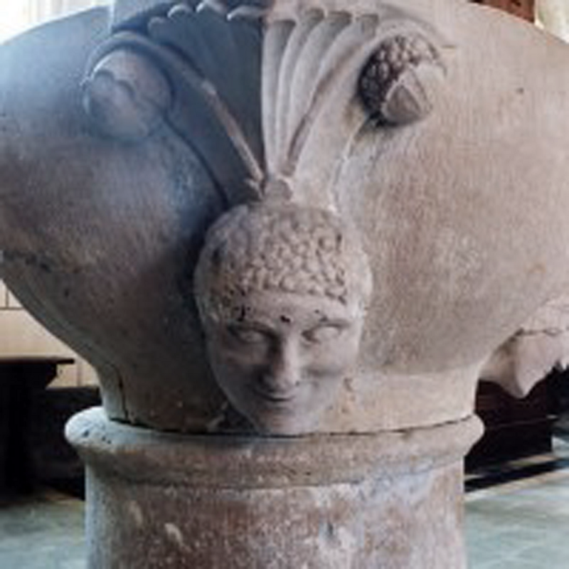 palmette-like with acorns (?) at the outer tips, above the two human heads