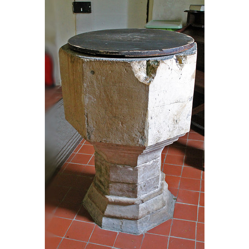 notice the larger damage at the corner; the thin round drilled hole for a metal staple is visible here; it was probably the expansion of the metal that split the stone, a common occurrence in stone fonts where the expansion rates of metal and stone differ; notice also the plain cover -- Source caption: "The font is from the original church"