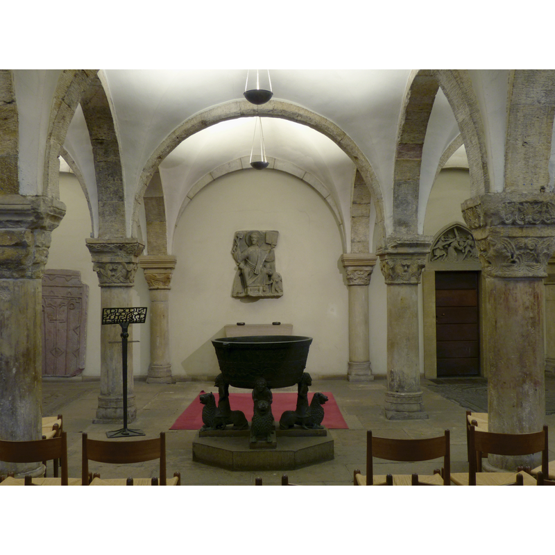 the font in the crypt of the cathedral -- Source caption: "Westkrypta des Bremer Doma mit dem romanischen Taufbecken und dem Relief von Jesus Christus als Pantokrator (Herrscher) aus der Mitte des 11. Jahrhunderts".