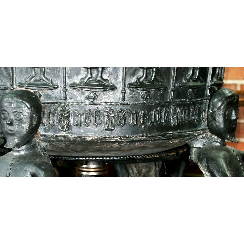used as separators in the inscription are a series of tiny figures, among which is a Madonna and Child; Mary appears o be crowned here, on the left