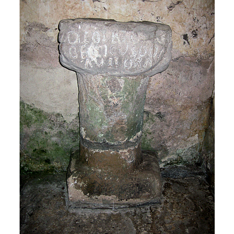Source caption: "On the north wall of the church of St Michael, facing the door is this Roman altar. According to the Herefordshire Sites and Monuments Database, "Inscribed RB altar, orig site unknown, as stood in the nave of St Michaels since 1909, in recess of the former N doorway. The base was rediscovered in 1820 & the upper part some time later. In medieval times it was adapted for use as a stoup. Rev J Web well known antiquary found this relic in a cottage in Michaelchurch. It has evidently been used as a holy water stoup, but was used as a mortar by the village doctress in whose possession it was found having been removed from behind the church door.. it had been broken & the upper part only was first found, subsequently discovered the rest & the 2 have now been properly joined together." Pevsner writes, " A Roman altar, partly cut back to form a rough capital. It bears the inscription Deo Tri-(vii)Beccicus donavit ara(m).'"