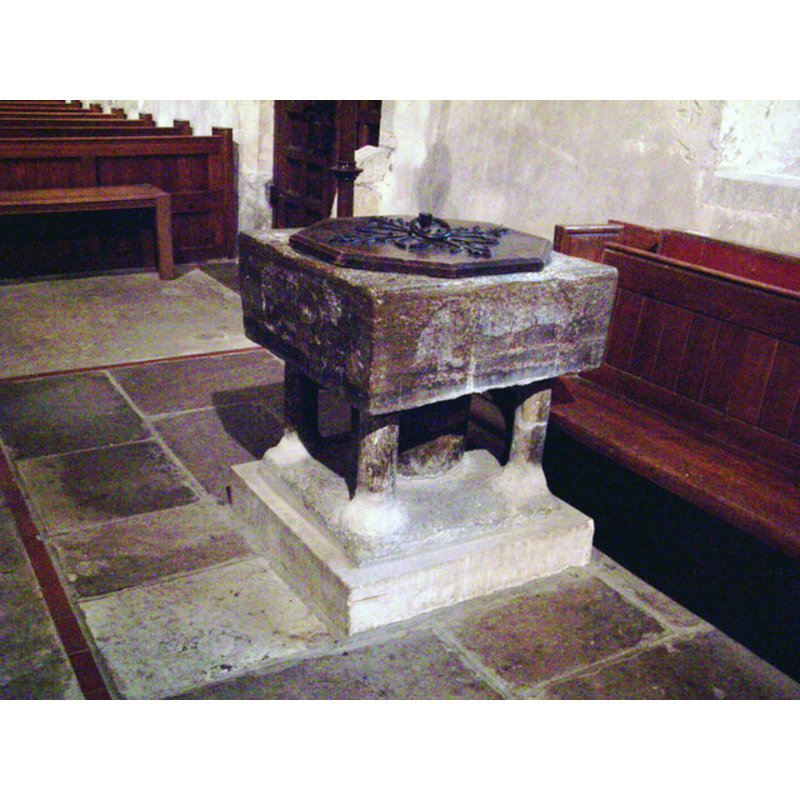 Source caption: "St Mary's Church, Buriton - Font. The font is Purbeck marble and is 12th century. The wooden cover was a gift from Holy Trinity Church, Aldershot, in 1928. On either side of the font are the lead insertions, which were designed to hold staples. An order of 1234 directed that fonts be covered and locked to prevent water being taken away for sacrilegious purposes."