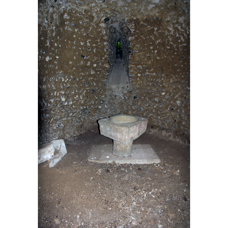 Source caption: "Apsidal chancel and rescued 12th century font in the buried church of St.Nicholas. The grade II listed Norman crypt of c1100 was superseded by a later 12th century church above ground level. The church was pulled down in 1875 and the existence of the crypt was forgotten until 1929 when it was rediscovered and excavated by Rev.E.P.Gough. A service is conducted once a year to maintain its consecrated status."