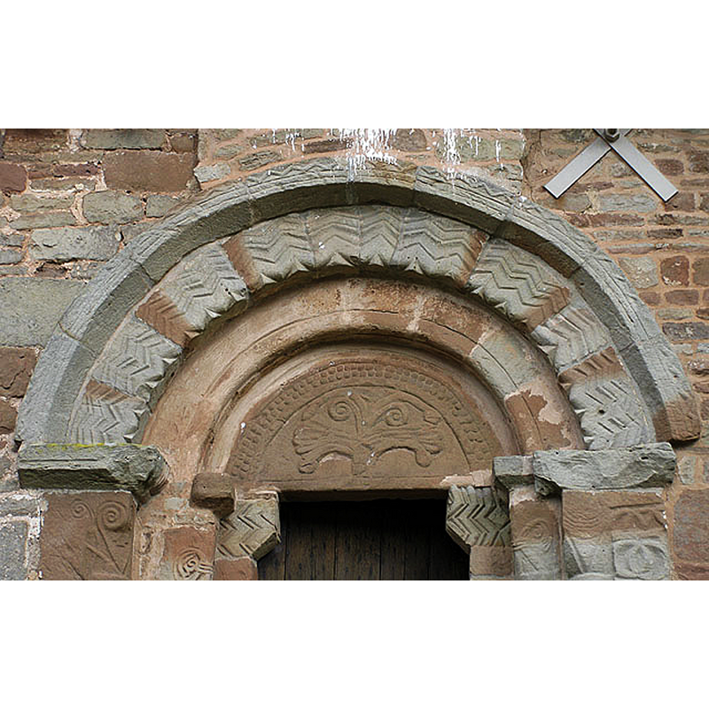 Source caption: "Yatton Chapel. Parts of the chapel, e.g. the south doorway, date from the 12th century. The doorway is typically Norman in style with rounded arch, chevrons and tympanum. A simple tree of life is carved on the tympanum."