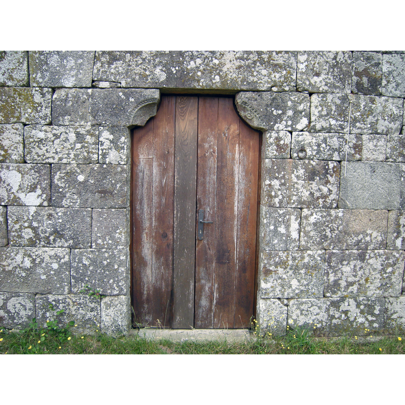 Source caption: "La puerta occidental conserva las primitivas mochetas que soportan el dintel. El resto de la fachada está totalmente reconstruido."