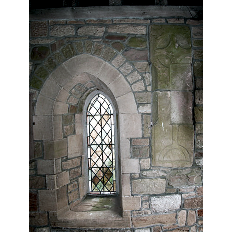 Source caption: "The South porch of All Saints was rebuilt in 1870 and has a pointed outer archway and two side lights. It contains several ancient worked stones in its walling, one is part of a small octagonal shaft, and another is a small early moulded capital, a third is a base, a fourth a piece of edge roll mould and a fifth a Saxon stone with interlacing pattern, while the sixth and largest is a 13th century coffin slab."