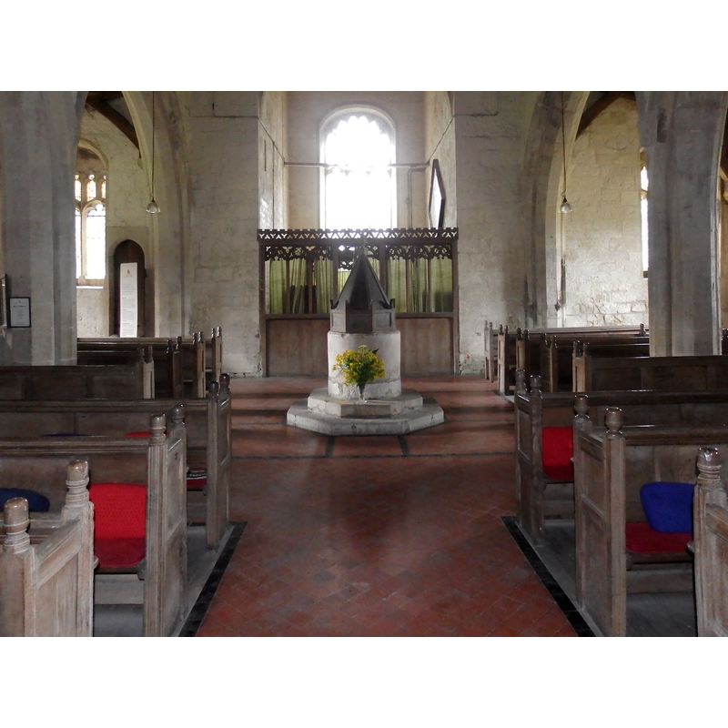 the font and cover at the west end of the nave; behind is the bestry, in the tower space
