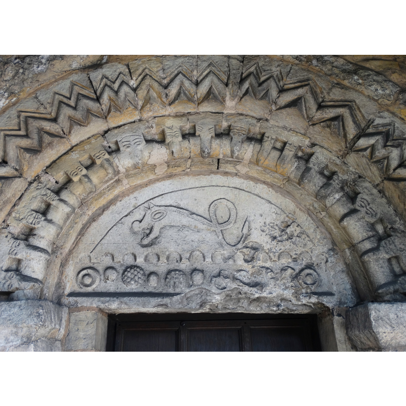 Source caption: "Tympanum over the south doorway, Austerfield church. It is believed that this curious tympanum is eighth century though The Parish Church of Saint Helena is reckoned to be eleventh century. It has been suggested that the tympanum's carvings, surrounding the figure of a dragon, symbolise the means by which Easter Day is calculated in the Christian church."