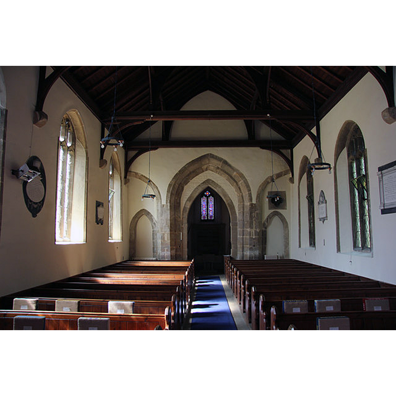 Source caption: "St.Margaret's nave. View west in St.Margaret's nave to the enigmatic tower arch and flanking early 14th century arches. There were presumably arcades that extended around the tower, most likely reduced in the 18th century restoration when the smaller tower arch was also inserted." -- the font is located beneath the tower, practically invisible in this image
