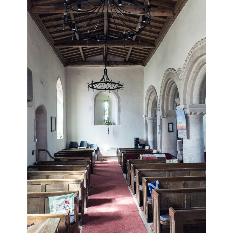 the baptismal font is partially discernible in the north aisle, behind the arcade on the right