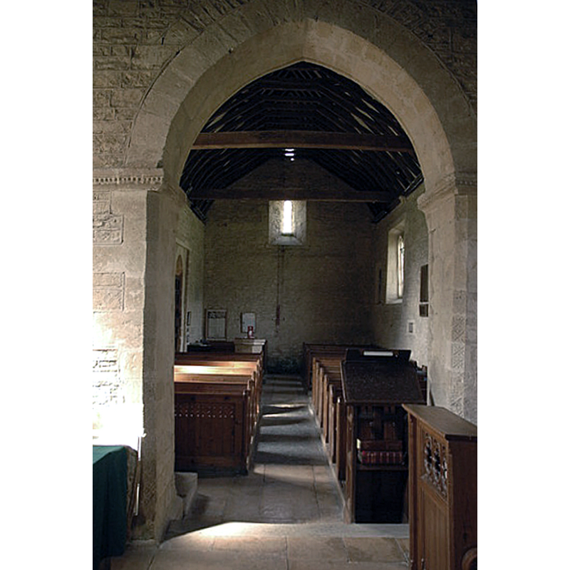 view of the nave and west end through the chancel arch, with a partial view of the font at the far end, opposite the south entranceway