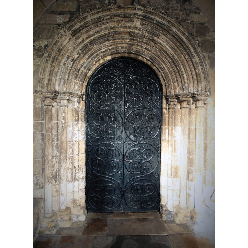 Source caption: "The south door of Worksop Priory Church. Made from yew, this door was constructed around 1250 and is decorated with some of the finest iron scrollwork to be found anywhere in England. The stone arch is even older - part of the original Norman structure. On its thin columns you can still see examples of Jerusalem crosses, lightly hacked into the stonework by crusaders of the thirteenth and fourteenth centuries."
