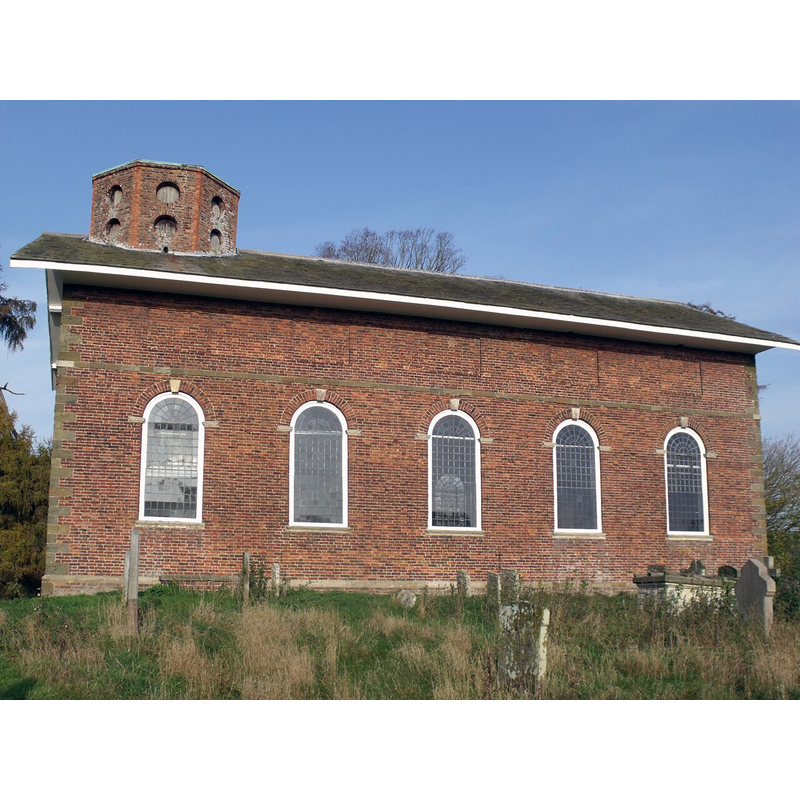 Source caption: "The present building was erected in 1725 in the time of George Langton (1647-1727) [...] Although records state that there was a church and resident priest at Langton before the Norman Conquest all that remains from earlier churches are the font and monuments to John Langton (d 1533) and Roger Langton (d1625) in the floor near the inner door [...] The plain red brick exterior of the church is crowned by a roof with wide overhanging eaves. In 1792 the original roof was stripped of lead, possibly for bullets for the Napoleonic wars, and the roof pitch increased to take the present slate roof. In 1825 the octagonal bell turret with bull’s eye louvres was added though the bells hang in a remarkable frame within the roof gable below the bottom of the tower."