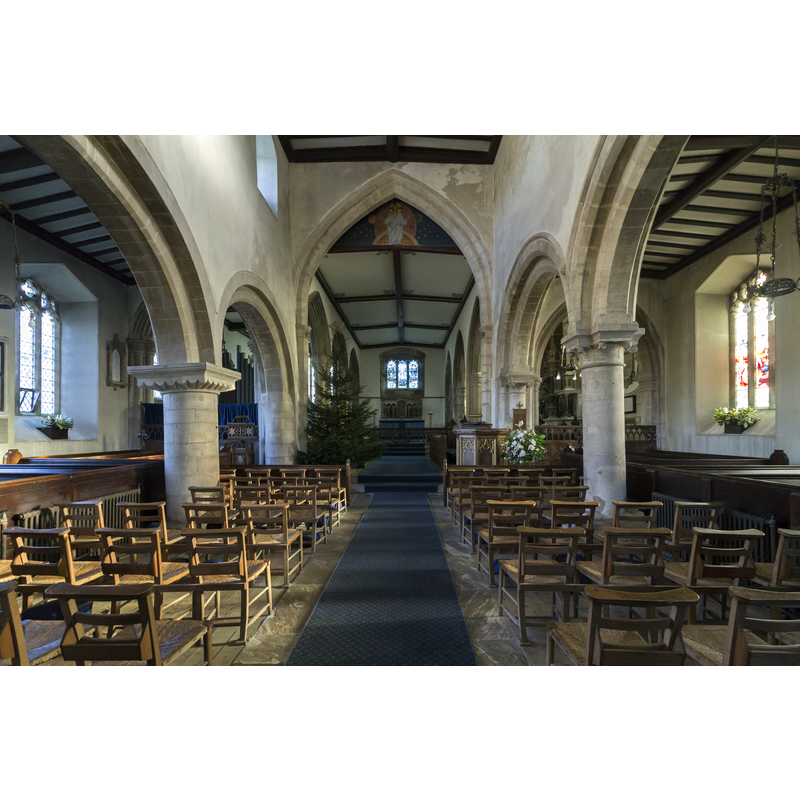 Source caption: "The north arcade is said to date from around 1066 thus it would seem that the church was originally a small Norman church of which only the Nave and Tower remain. The walls and windows of the North and south aisles of the nave date from the Restoration in 1846. Sometime in the 14th century the chancel arch was built, but the chancel it led to has gone. The arch leading to the tower was built about the same time and probably it was then that the nave walls were heightened and a clerestory provided. In 1846 the roof of the chancel was lowered and a low lath and plaster arch constructed under the chancel arch that now exists. This was removed in 1935 and the old arch – sadly hacked about – was revealed. It was impossible to raise the chancel roof, so the space in the apex of the arch was filled by a painting: “Our Lord in Glory”, by Miss Jessie Bayes. In the 15th century, all that now exists beyond the chancel arch and beyond the eastern arches of the nave aisles – was entirely rebuilt."