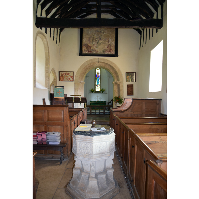 Source caption: "Syde Church (St. Mary the Virgin), Gloucestershire [...]  Looking towards the Victorian chancel is the 12th Century Norman nave but it could be late Saxon altered/rebuilt by the Normans. Above the chancel arch ('the place of doom') are the arms of Charles II. The box pews are 18th Century Georgian." -- showing the west side of the font