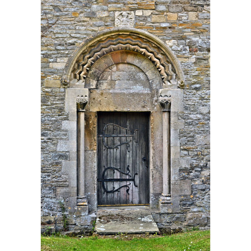 Source caption: "St Andrew, Churcham. The North door - a 19th century restoration. The sculpture above has experts puzzled as to date, but it could be as early as the 3rd century."