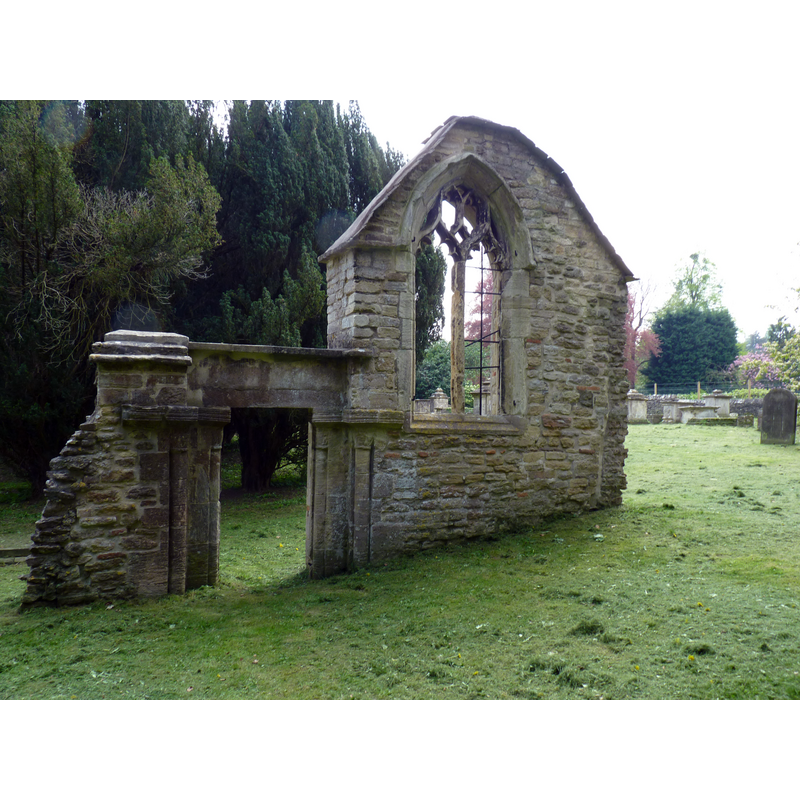 Source caption: "Old St Mary's Church Site, Woodchester. The ancient parish church of ST. MARY stood at the northern extremity of the parish and comprised chancel, nave with south aisle and porch, and west tower. On the north side of the church was a raised, covered passage from the church to the edge of the churchyard for occupants of the Priory. The survival of a 12th-century doorway and chancel arch suggests a rebuilding at that date, although most of the external features of the nave and chancel appear to have been late medieval and the tower was probably built in the 15th century. The church contained a monument with effigies to Sir George Huntley and his wife and some wall monuments by Franklin of Stroud and John Ricketts the elder of Gloucester. In 1851 the church was said to have been much modernized, probably in 1815, and 'encumbered with the most hideous pews and galleries'. In 1858 a new Rector George Henry Evans was appointed after eighteen years of service in several parishes in India and a record of getting new churches built. In 1861 it was decided to replace the church and graveyard, which contained a number of carved stone tomb-chests and headstones and remained in use for some further years, with a new building on a site further south. The land was donated by Mrs. Edward Wise and stone from the old church was used in the new building, which comprised chancel, nave with north aisle, south tower with broach spire, and south porch. The new church was consecrated in September 1863"