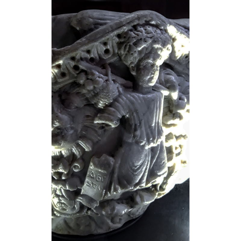 human figure with flowers on his head carries a basket of fruit on his back