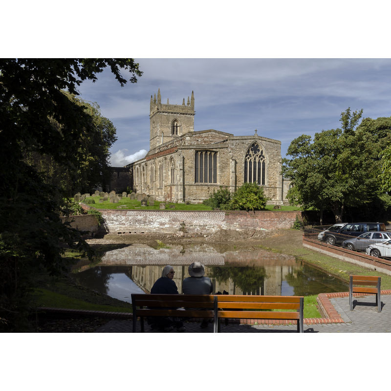 Source caption: "Barton on Humber has two churches located close to each other, the older being Saint Peter's which dates from the late 10th century, and is mentioned in the Domesday Book of 1086. It is unsure why a second church was built, although Saint Peter's was much smaller at the time, and the town was prosperous. St Mary's dates from the 12th century onwards, and has a nave with north and south aisles, a western tower, a chancel with south Chapel, and a south porch with parvis. The north arcade dates from the mid to late 12th century, and is of five bays plus a taller, later eastern arch. The piers are circular and the round arches have zigzag decoration. The south arcade is of four bays and dates from circa 1300. It has octagonal columns similar to those in Lincoln Cathedral, topped with water leaf capitals. Both the aisles were later enlarged. The tower dates from the 13th century, and has decorated parapets with eight pinnacles from a later date. There was initially a spire on top. The tower arch has stiff leaf capitals and keeled shafts. The south porch has a reset early 13th century archway, and an upper chamber with a door high in the nave, once reached by a stairway. In the 14th century the south chapel was built with a three bay arcade towards the chancel. The capitals contain a number of green men, many of its windows are reused In the 15th century a clerestory was added to the nave. The east window of the chancel was reduced in height when the gabled roof was lowered."