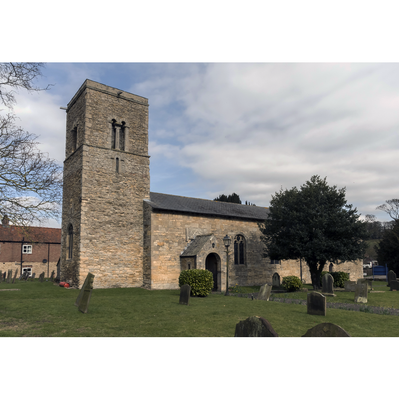 Source caption: "The church dates from the late 11th century onwards, and is built of ironstone and limestone with slate roof. There is a west tower, nave and chancel in one, with a south porch. The tower is late 11th century with a 14th century west window, there is also a small round headed 11th century window above. The tower was restored in the 19th century. The east side has earlier roofline visible beneath the Bell opening and clock. The nave has 19th century windows, the chancel was rebuilt in the late 16th century (to take the Wray monument). The south side of the chancel has a blocked opening to the east and a small 12th century doorway to the west. The tower arch is 11th century with round head, the chancel arch is 13th century. Inside there are 19th century pews, lectern, pulpit and altar rail. The font is 20th century. The large monument to Sir Christopher Wray is on the north side of the chancel. There is also a large white marble monument to Elizabeth Saunderson. The church was restored in the 19th and 20th Centuries."