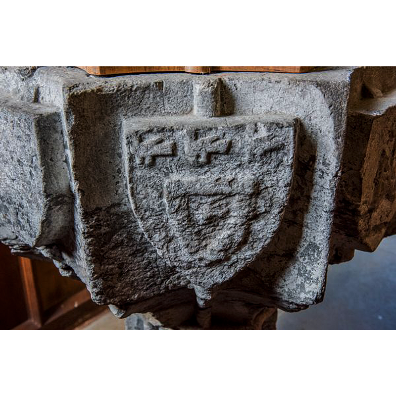 a detail of the basin of the restored heraldic font, originally from the Parish Church of All Saints in Newcastle-upon-Tyne, as displayed inside the Church of St Wilfrid, Kirkharle -- the eroded emblems on the shields have been reproduced on the modern lower base