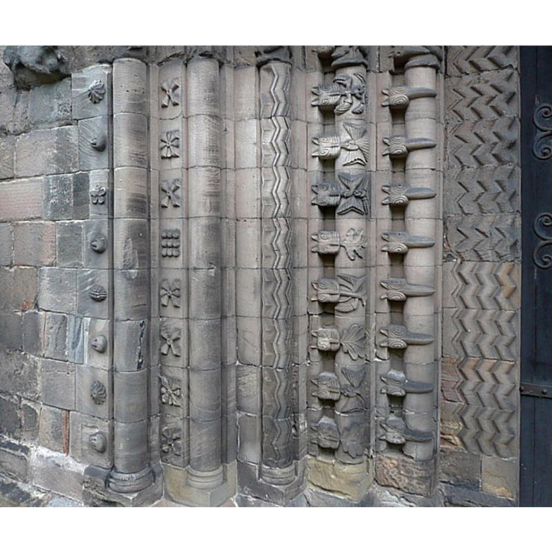 Source caption: "Detail of the western doorway of St Mary's Church, Tutbury. This shows the shafts on the left side of the Norman doorway, which has six richly carved receding arches. These shafts have been partly restored, but the arches above are original."