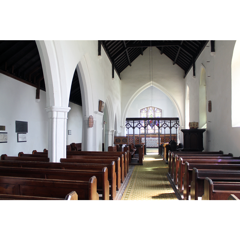 Source caption: "The present lectern, made locally in 1871, stands in front of a massive pillar, which was evidently the foundation of what was once the chancel arch, the old chancel ending at the site of the attractive oak screen. The arches of the nave are early English, the chancel arch and church itself perpendicular, while the windows show three different styles."