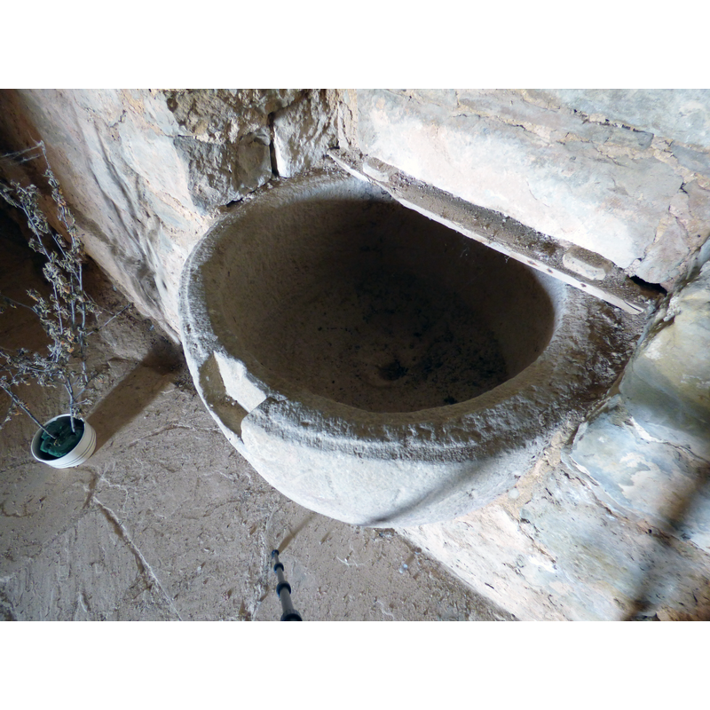 showing the cut made on the upper rim to fit a cover lock, and the central drain -- some remains of a modern wooden cover can be discerned at the back
