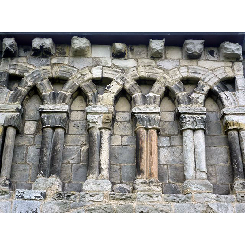 Source caption: "Blind arcades at Dalmeny Kirk. These are above the doorway on the south wall of the Norman nave. Note the carved heads above them which are very similar to those at Leuchars in Fife. They represent animals of some sort, though it isn't clear which."